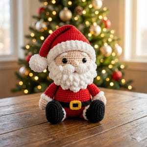 Può includere: Bambola di Babbo Natale all'uncinetto con abito e cappello rossi, stivali neri e barba bianca. La bambola ha una fibbia dorata ed è seduta su una superficie di legno. Un albero di Natale illuminato è sullo sfondo.