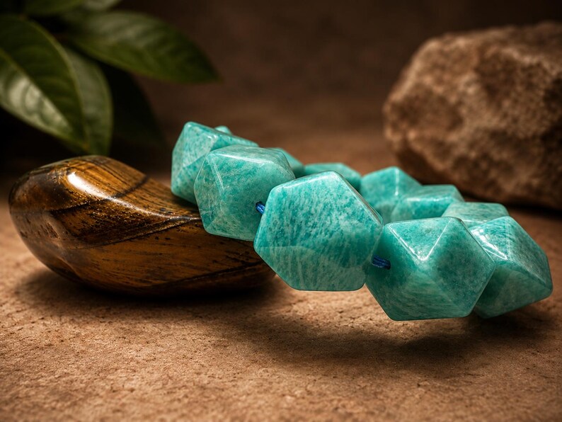 Pu&ograve; includere: Un braccialetto composto da perline esagonali sfaccettate di un vivace colore verde acqua. Le perline sono infilate su un sottile cordino blu, creando un motivo geometrico. La superficie di ogni perlina presenta variazioni naturali di colore.
