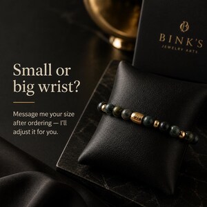 May include: A beaded bracelet with dark green and gold beads, displayed on a black cushion. The bracelet has a gold accent piece. The text on the image reads "Small or big wrist?" and "BINK'S JEWELRY ARTS."