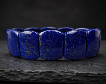 Può includere: Un bracciale composto da perline rettangolari in lapislazzuli levigato. Ogni perlina presenta un colore blu profondo e saturo con inclusioni naturali di pirite dorata sparse sulle superfici lisce e lucide dei segmenti di pietra.