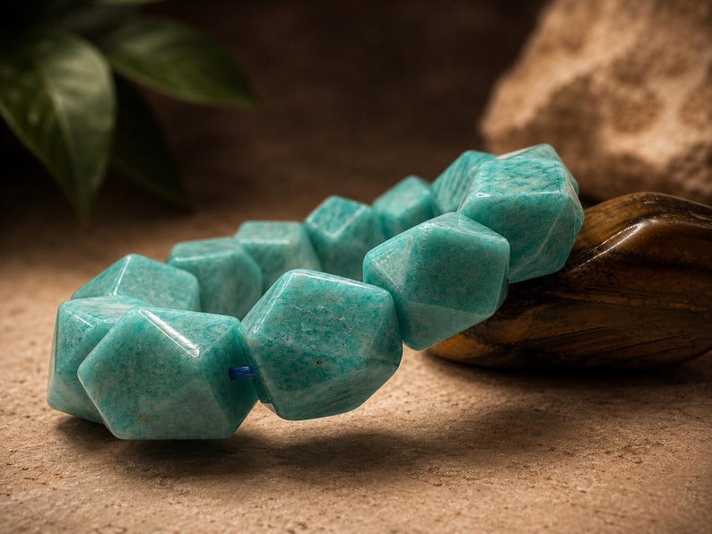 Pu&ograve; includere: Un bracciale composto da perline geometriche sfaccettate di un vibrante colore verde acqua. Le perline hanno una finitura liscia e lucida e sono infilate su un sottile cordino blu, creando un aspetto strutturato e angolare sull'intero pezzo.