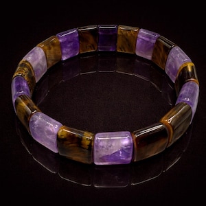 May include: A bracelet featuring rectangular beads in shades of purple and brown. The alternating colors create a striking contrast, with the purple beads appearing translucent. The bracelet is designed to be worn around the wrist.