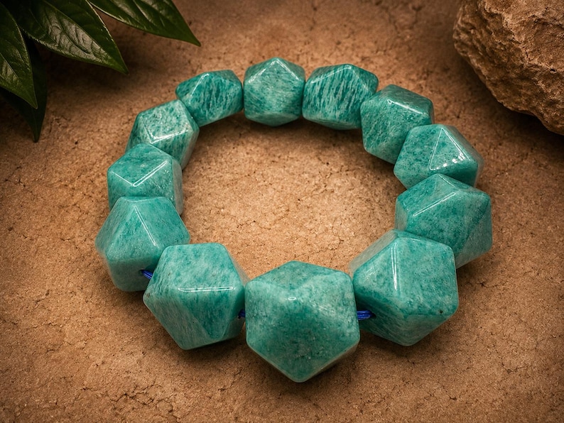 Pu&ograve; includere: Un braccialetto circolare composto da dodici perline geometriche sfaccettate di un vibrante colore verde acqua. Le perline sono infilate su un sottile cordino blu, creando un aspetto strutturato e angolare con una superficie liscia.