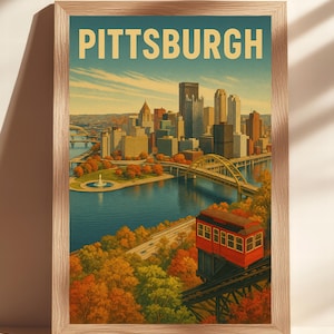 Op de afbeelding: Een ingelijste print met een vintage illustratie van Pittsburgh. Het kunstwerk toont de skyline van de stad, bruggen en een rode kabelbaan tegen een achtergrond van herfstbladeren en een blauwe lucht. Het woord "PITTSBURGH" staat bovenaan.