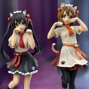 May include: Two anime-style figurines of young women in maid outfits with cat ears. One has black hair and a black skirt, the other has brown hair and a red skirt. Both are in a playful pose.