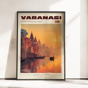 May include: Framed art print featuring a sunset over Varanasi, India. The artwork displays the city's architecture along a river, with boats and figures in silhouette. The text "VARANASI" and "UTTAR PRADESH, INDIA" are at the top, with coordinates at the bottom.