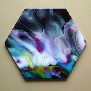 May include: Hexagon-shaped abstract art piece with a glossy finish. The artwork features a fluid design with a mix of colors, including black, white, teal, purple, and yellow. The colors blend and swirl together, creating a unique and eye-catching design.
