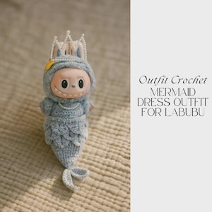 Pode incluir: Um conjunto de vestido de sereia de crochê azul claro para uma boneca Labubu. O conjunto inclui um top com capuz com um colar de pérolas, uma cauda de sereia e uma coroa. O texto à direita diz "Outfit Crochet MERMAID DRESS OUTFIT FOR LABUBU."