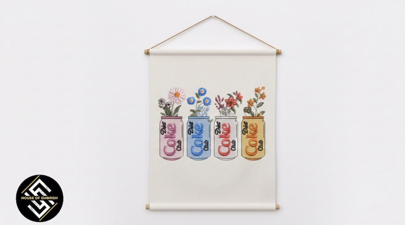 May include: A wall hanging featuring four Diet Coke cans, each holding a different arrangement of flowers. The cans are pink, blue, red, and yellow, with the words "Diet Coke Club" printed on them. The artwork is displayed on a cream-colored fabric.