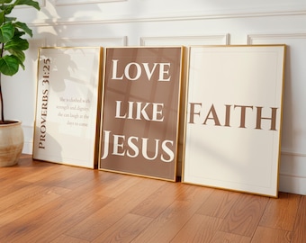 Może przedstawiać: Trzy oprawione wydruki artystyczne ze złotą obwódką. Wydruki wyświetlają słowa "PROVERBS 31:25", "LOVE LIKE JESUS" i "FAITH" w kroju pisma szeryfowego. Kolory tła to beżowy i brązowy. Wydruki oparte są o białą ścianę na drewnianej podłodze.