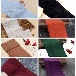 Puede incluir: Surtido de adornos de encaje en varios colores, incluyendo azul claro, negro, blanco, naranja, marrón, verde, burdeos y morado. Cada adorno presenta un patrón floral detallado y bordes festoneados. El encaje se muestra en rollos.