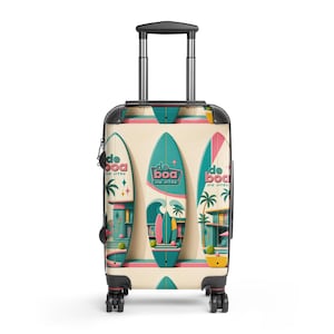 May include: A rolling suitcase with a cream-colored background featuring a repeating graphic pattern of teal surfboards, palm trees, and buildings. The text "de boa JIU JITSU" is printed on each surfboard graphic. It has a black handle and wheels.