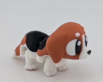 May include: A 3D-printed figurine of a cartoon beagle dog. The dog has a brown head and ears, a black back, and white legs and belly. It has large, expressive eyes and a small black nose. The figurine is on a white background.