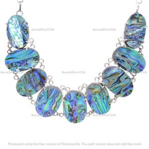 Op de afbeelding: Een ketting met ovale abalone schelpen hangers in blauw, groen en paars, verbonden door een zilveren ketting. De schelpen hebben een iriserende glans. De tekst "AuraSilverUSA" is zichtbaar.
