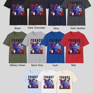 May include: A collection of short-sleeved t-shirts in various colors, each featuring a graphic of a soccer player and the word "FRANCE". Colors include black, dark chocolate, navy, dark heather, military green, sport grey, royal, red, light blue, white, and natural.