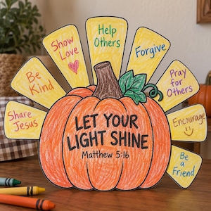 Może przedstawiać: Papierowa dynia z brązową łodygą i zielonym liściem, zawierająca tekst "LET YOUR LIGHT SHINE Matthew 5:16". Żółte papierowe pióra wystają z tyłu, każde z odręcznie napisanymi zwrotami, takimi jak "Be Kind", "Show Love" oraz "Help Others".