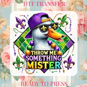 May include: DTF transfer with a cartoon duck wearing sunglasses, a purple cap, and Mardi Gras beads. The duck is set against a diamond-shaped background with fleur-de-lis accents. Text reads "THROW ME SOMETHING MISTER" and "READY TO PRESS."