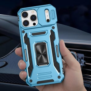 May include: A light blue phone case with a geometric design. The case has a built-in ring holder and a sliding camera cover. The case is held in a person's hand.