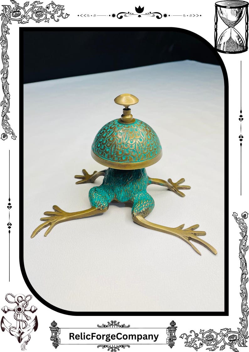May include: A unique brass frog-shaped bell with a turquoise patina. The bell has a dome-shaped top with intricate patterns and a small knob. The frog's legs are outstretched, giving it a whimsical appearance. The text "RelicForgeCompany" is at the bottom.