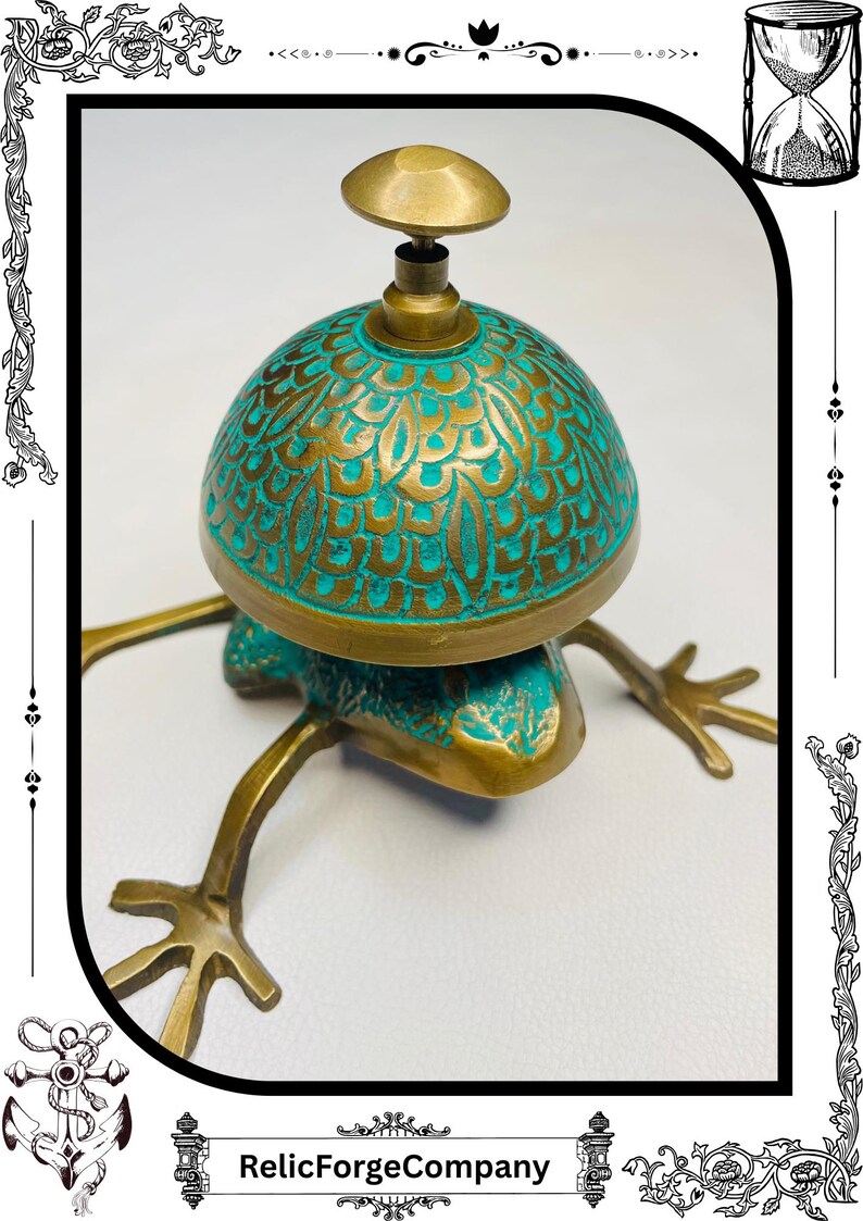 May include: A brass frog-shaped bell with a turquoise and gold dome. The bell has a detailed floral pattern and a small brass knob on top. The frog's legs are extended, and the bell is set against a white background.