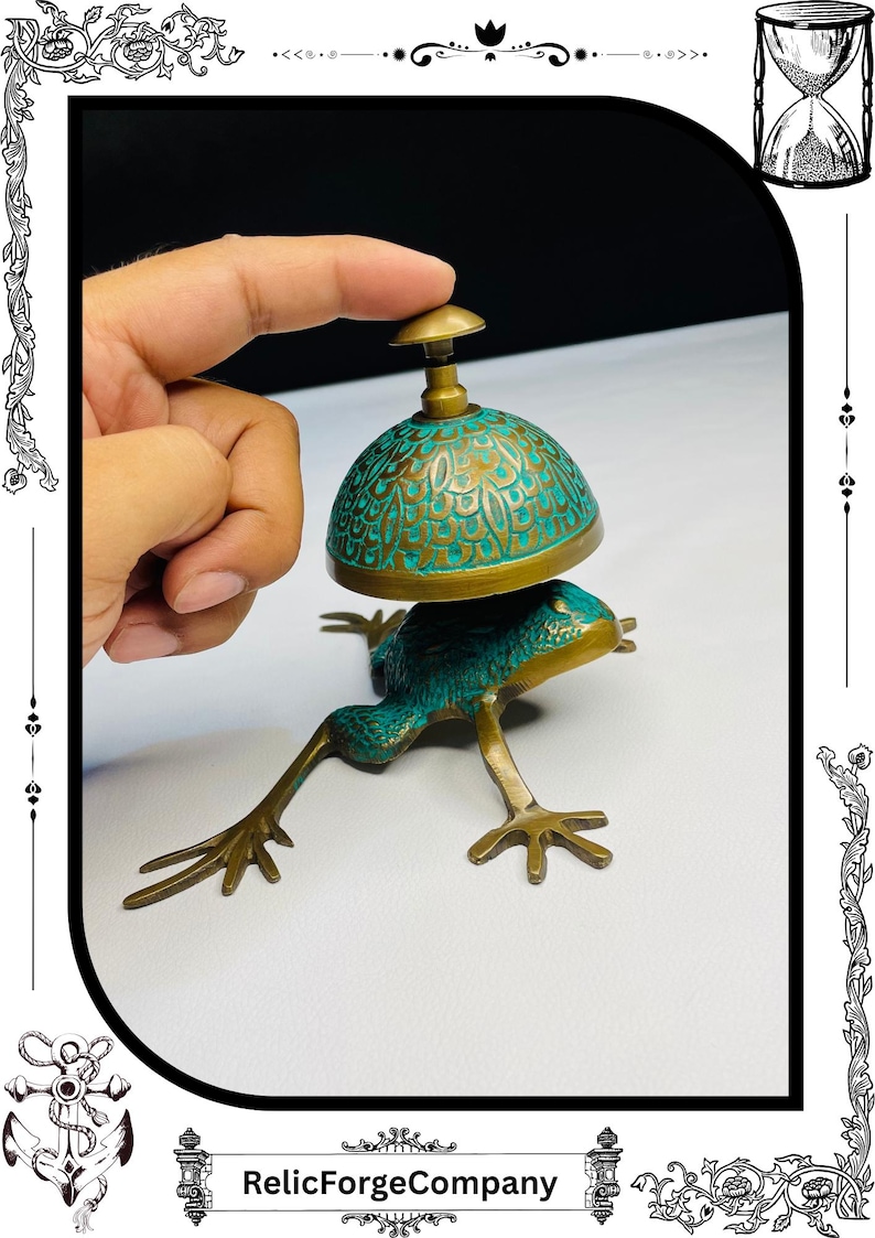 May include: A brass frog-shaped bell with a turquoise patina dome and gold accents. The bell is being pressed by a finger. The base of the bell is a frog with outstretched legs. The words "RelicForgeCompany" are at the bottom.