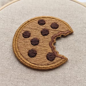 May include: A set of three ceramic mugs with a speckled, matte finish. The mugs are in shades of cream, light brown, and dark brown. Each mug has a simple, minimalist design and a rounded handle.