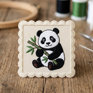 May include: Embroidered panda bear patch with a scalloped edge. The panda is black and white, holding a green bamboo stalk. The patch is on a beige background, with sewing supplies in the background.