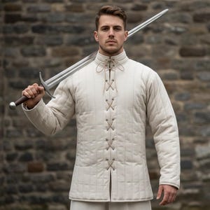 May include: Cream-colored quilted jacket with a high collar and a laced front closure. The jacket has long sleeves and a grid-like pattern. A long, silver sword is held over the shoulder.