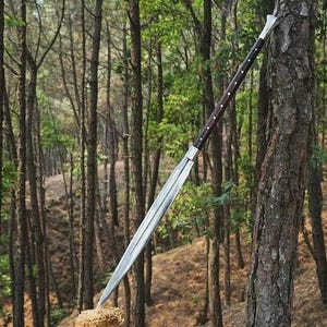 May include: A white ceramic mug with a black handle and the text "But First, Coffee" in a bold, black font. The mug is set against a blurred background, suggesting a cozy setting.
