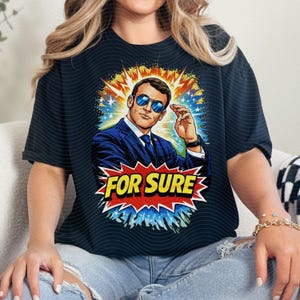 以下が含まれることがあります： 黒いTシャツ。スーツとサングラスをかけた男性の漫画風イラスト。グラフィックには、赤と黄色の爆発で「FOR SURE」というテキストが含まれています。