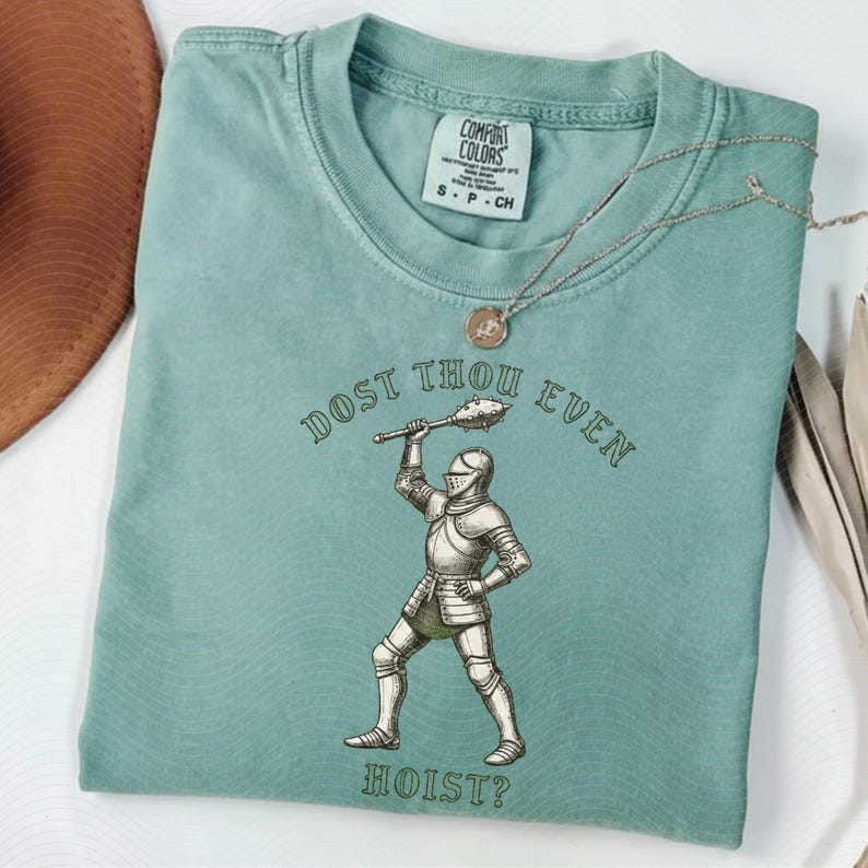 May include: A seafoam green t-shirt with the text "DOST THOU EVEN HOIST?" and an illustration of a knight in armor holding a mace. The shirt has a Comfort Colors tag and a small necklace.