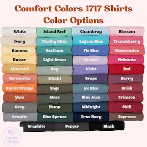 May include: A display of Comfort Colors 1717 shirts in various colors, including white, blue, green, and pink. The image showcases a wide range of color options, with each shirt neatly folded and labeled with its respective color name.