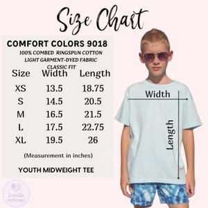 May include: A light blue youth midweight tee shirt with a size chart. The chart shows measurements in inches for sizes XS to XL. The shirt is made of 100% combed ringspun cotton and light garment-dyed fabric.