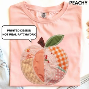 May include: A light pink t-shirt featuring a printed apple design. The apple is composed of various fabric patterns, including gingham, floral, and polka dots. The text "PEACHY" is at the top right. The text "PRINTED DESIGN NOT REAL PATCHWORK" is in a speech bubble.