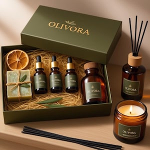 Könnte beinhalten: Olivgrünes Geschenkset mit dem Markennamen "OLIVORA" in Goldbuchstaben. Das Set enthält ätherische Ölflaschen, ein Seifenstück, eine Kerze und einen Reed-Diffusor. Die Kerze ist angezündet, und eine getrocknete Orangenscheibe ist sichtbar.
