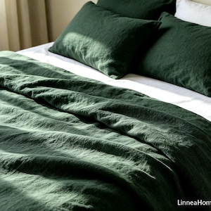 May include: A dark forest green bedding set featuring a duvet cover and two matching pillowcases. The fabric has a visible textured weave and is layered over white sheets. The text LinneaHome is printed in the bottom right corner of the image.