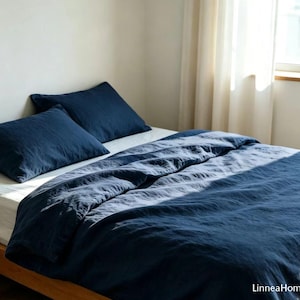 May include: A dark navy blue duvet cover and two matching pillowcases on a bed with white sheets. The bedding has a visible textured fabric finish. The text LinneaHome is printed in the bottom right corner of the image.