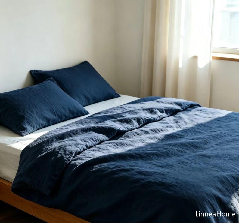 May include: A dark navy blue duvet cover and two matching pillowcases on a bed with white sheets. The bedding has a visible textured fabric finish. The text LinneaHome is printed in the bottom right corner of the image.