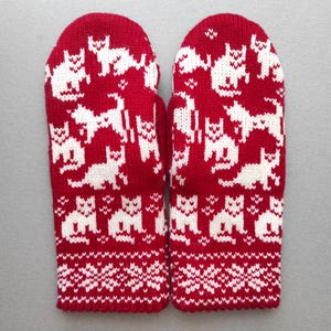 Può includere: Un paio di guanti a maglia rossi e bianchi. I guanti presentano un motivo ripetuto di gatti bianchi su sfondo rosso. I polsini hanno un design a fiocco di neve bianco. Progettati per calore e stile.