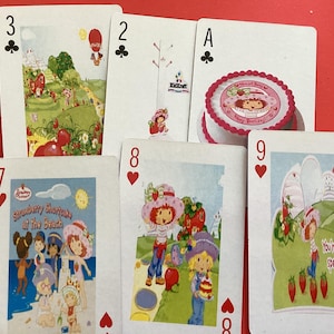 May include: A collection of playing cards featuring Strawberry Shortcake characters. The cards display various scenes and illustrations, including a birthday cake and the text "You're berry special!"