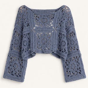 Könnte beinhalten: Ein blaues Häkeltop mit langen, ausgestellten Ärmeln. Das Oberteil hat ein quadratisches Musterdesign mit floralen Motiven. Der Ausschnitt ist weit, im Bootsausschnitt-Stil. Die Häkelarbeit ist detailliert und aufwendig und erzeugt ein strukturiertes Aussehen.