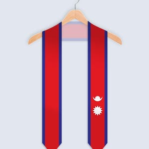 May include: A red and blue graduation sash featuring the flag of Nepal, displayed on a wooden hanger. The sash has a red background with blue borders and the flag's symbols.