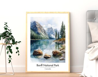 May include: A framed watercolor print of Banff National Park in Canada. The artwork depicts a serene lake surrounded by mountains, trees, and rocks. The text "Banff National Park" and "Canada" are printed at the bottom of the image. The frame is a light wood color.