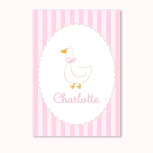 Pode incluir: Uma impressão listrada rosa e branca com um pato de desenho animado com um laço rosa. O pato está dentro de um oval branco com uma borda ondulada. O nome "Charlotte" está escrito em rosa abaixo.