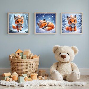 May include: Three framed art prints featuring adorable cartoon foxes in winter scenes. The foxes are wearing hats and scarves, set against snowy backgrounds. A wicker basket of wooden blocks and a large teddy bear are in the foreground.