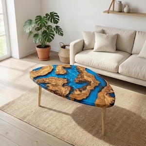 May include: Oval coffee table with a unique design. The table features a wooden surface with a blue resin river. The table has light-coloured wooden legs. The table is approximately 122 cm long.