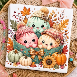 May include: A square print featuring three cute, round, smiling characters wearing winter hats inside a teal bowl. The scene is decorated with autumn maple leaves, berries, pumpkins, and a sunflower. A large gold bow is centred on the bowl.
