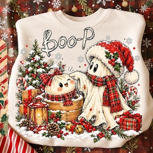 Può includere: Una felpa color crema con una stampa grafica raffigurante un fantasma con un cappello da Babbo Natale rosso e una sciarpa scozzese, un raviolo in un cestello di bambù, un albero di Natale, regali e una lanterna, con la scritta BOO-P in nero.