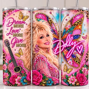 Puede incluir: Un vaso cilíndrico con el retrato de una persona rubia con una guitarra, mariposas y rosas rosadas. El texto dice Dream MORE Love MORE Give MORE y Dolly con un corazón. El diseño incluye estampado de leopardo y colores rosa vibrantes.