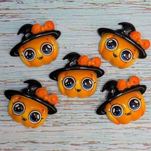 May include: Five orange pumpkin-shaped cabochons, each wearing a black witch hat adorned with an orange bow. Each pumpkin features large, glossy blue eyes, a small smile, and a smooth, rounded finish, arranged in a cluster on a light surface.